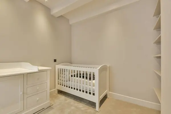a babys room with a cribt, dresser and changing table in the wall is painted white
