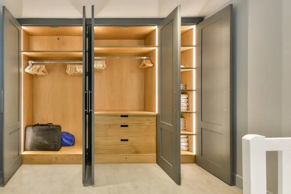 stock image a walk - in closet with clothes hanging on the wall and an open door that leads to a bathroom area