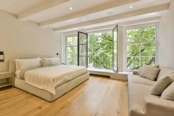 a bedroom with wood flooring and large windows overlooking the trees in the distance is an image of a living room
