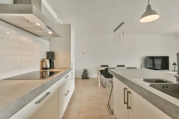 a kitchen and dining area in a modern apartment with white walls, wood flooring and light fixtures on the ceiling