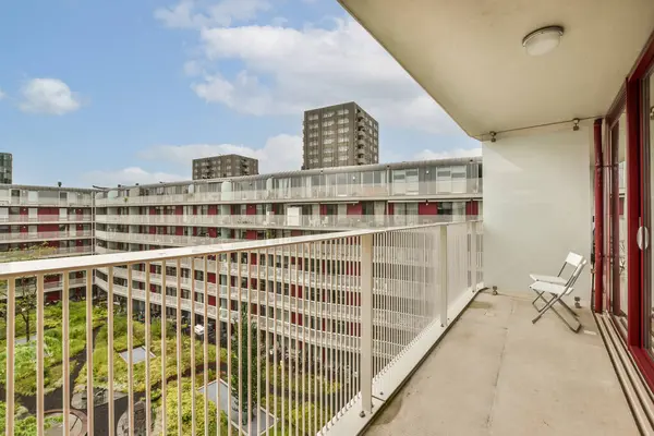 Arka planda bazı binalar ve fotoğrafın diğer tarafında yeşil çimenler olan bir balkon açık mavi gökyüzü.