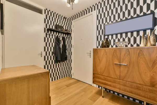 a bedroom with black and white patterned wallpaper on the walls, wooden furniture in the closet is next to the bed