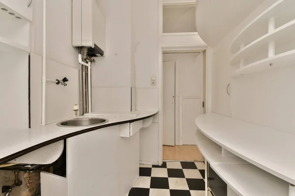 a kitchen area with black and white checkered tiles on the floor, and a sink in the corner to the room is empty