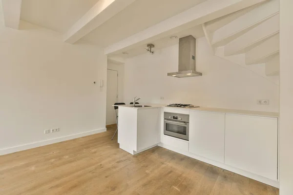 an empty kitchen with white cabinets and wood flooring in the middle of the room, there is a stove
