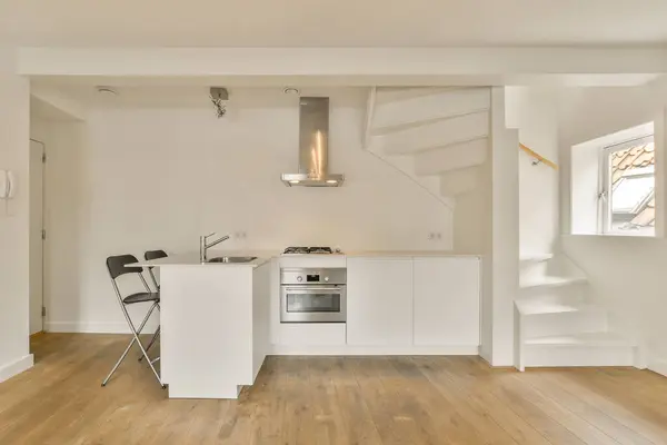 an empty kitchen and dining area in a house with wood floors, white walls and wooden flooring the room is very clean