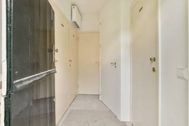 Boş bir koridor. Duvarda ya da soldaki kapıda nesne ya da insan yok. Odada sadece bir kişi var.