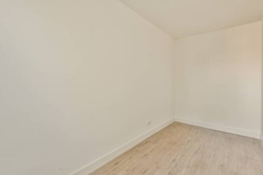 Beyaz duvarları ve ahşap döşemeleri olan boş bir oda. Duvarlar açık gri renge boyanmış. Çok temiz görünüyor.