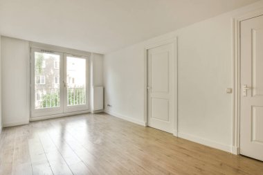 Beyaz duvarları ve ahşap döşemeleri olan boş bir oda.