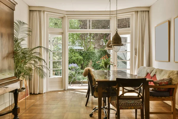 a dining room with wood flooring and large windows looking out onto the garden outside, as well in this photo