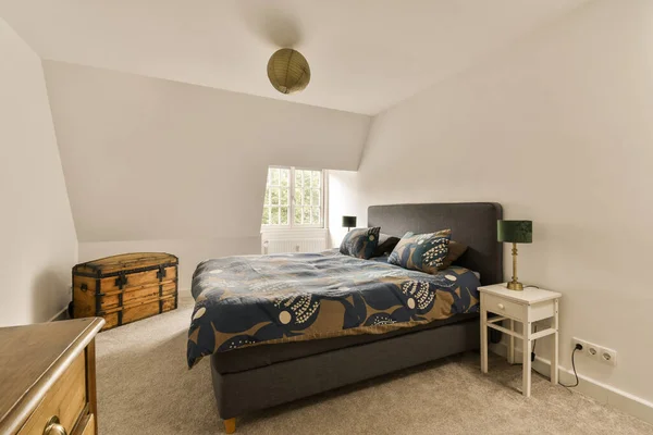 a bedroom with a bed, dressers and lamp on the wall in front of the bed is white walls