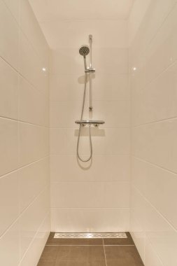 Duvarlarında beyaz fayanslar olan bir duş modern tarz banyo alanında kahverengi ahşap döşeme temiz ve hazır.