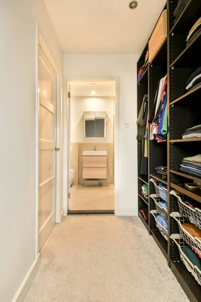 a walk - in closet with lots of clothes on the shelfs and shelves next to the door is open