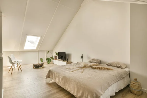 a bedroom with white walls and wood flooring the room is well lit by the light coming from the window