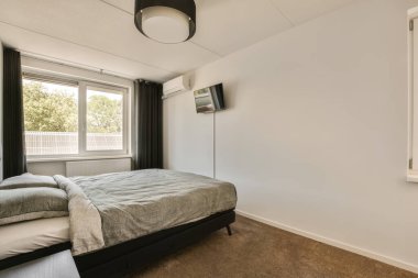 Yatak odası, pencerenin önündeki duvarda televizyon ve yatak odası arka bahçeye bakıyor.