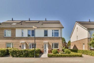 Aynı bölgede iki ev, biri beyaz, diğeri de camlarında siyah süsleme olan kırmızı.