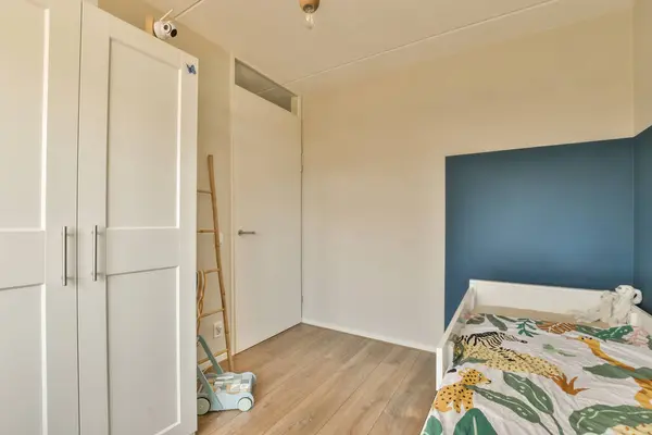 a bedroom with blue walls and white cupboards on the wall, next to a bed in a wooden floor