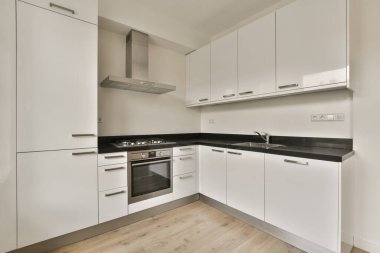 Güney Londra 'da bir apartmanda, duvarında beyaz dolaplar ve siyah tezgahlar olan bir mutfak.
