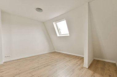 Beyaz duvarları ve ahşap döşemeleri olan boş bir oda. Köşesinde küçük bir pencere var.