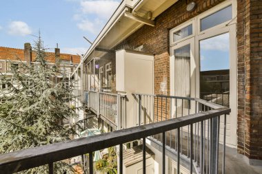 Ön planda ağaçlar ve fotoğrafın diğer tarafında binalar olan bir balkon.