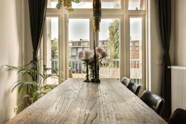 büyük pencereli bir odada bir masa ve sandalyeler şehir merkezine bakıyor.