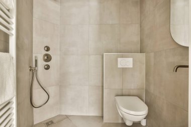 Tuvaleti, duşu ve havlusu olan bir banyo beyaz fayanslı bir duvar görüntüsüdür.