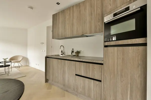 a kitchen with wood cabinets and an oven on the wall next to the counter space in the room is white
