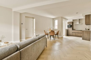 Bir apartman dairesinde ahşap döşemeli ve beyaz duvarlı bir oturma odası.