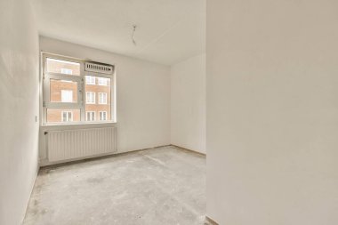 Beyaz duvarları olan boş bir oda ve pencerenin önünde duran hiç kimse dışarı bakmıyor.