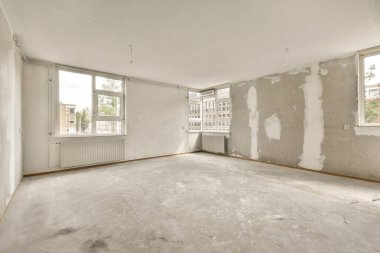 Beyaz duvarları ve her tarafı kuru alçıyla kaplı boş bir oda. Duvarda bir pencere var.