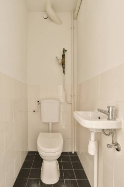 Yerde siyah beyaz fayanslar olan küçük bir banyo, duvarda lavabo ve tuvalet boyalı.