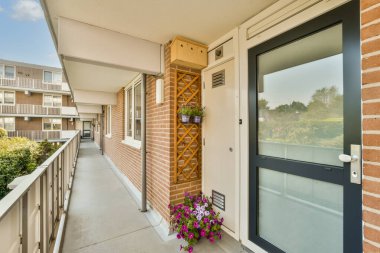 Ön kapısında çiçekler olan bir apartmanın dışında ve fotoğraftaki pencereler içeriden çekiliyor.