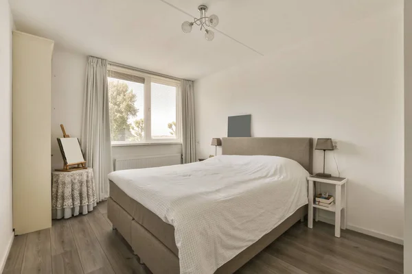a bedroom with wood flooring and white walls, including a large bed in the room has a ceiling fan