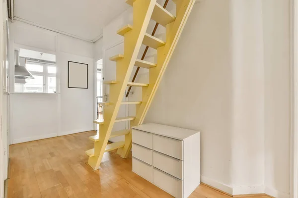 an empty room with some stairs in the middle part of the room is white and there is a yellow staircase leading up to the