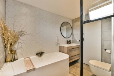 Duvarında altıgen fayanslar, köşesinde ahşap dolaplar ve tuvaleti olan modern bir banyo.