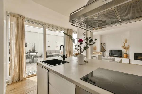 a kitchen and living room in a residential area with sliding glass doors that open onto the patio to an outdoor terrace