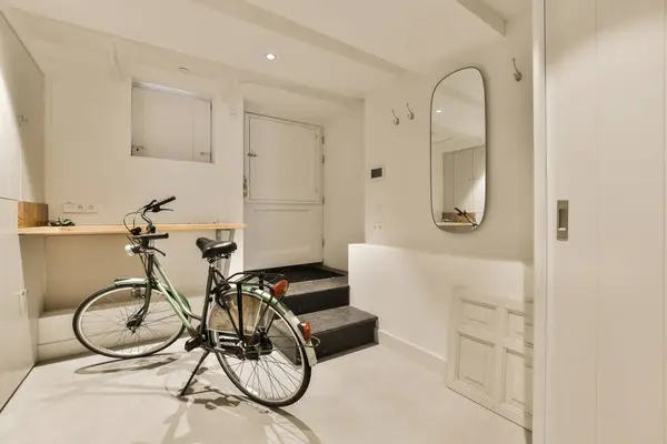 a room with a bike parked next to the door and a mirror hanging on the wall above it thats attached storage space