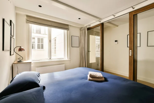 a bedroom with a bed, mirror and closet space in the photo is taken from the window to the other room