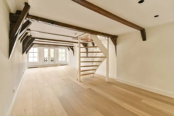 an empty living room with wood flooring and exposed beams on the ceiling above it is a staircase leading up to the second floor