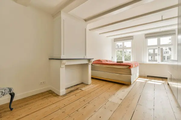a bedroom with wood flooring and white walls, including a small bed in the corner of the room to the right is a