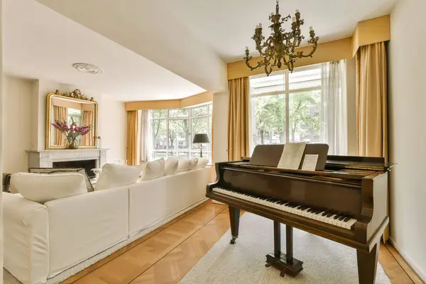a living room with a piano in the middle and a grand piano on the right side of the room there is a chandel