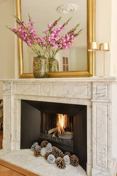 a fireplace with flowers and pine cones on the mantels in front of the fireplace is a mirror above it