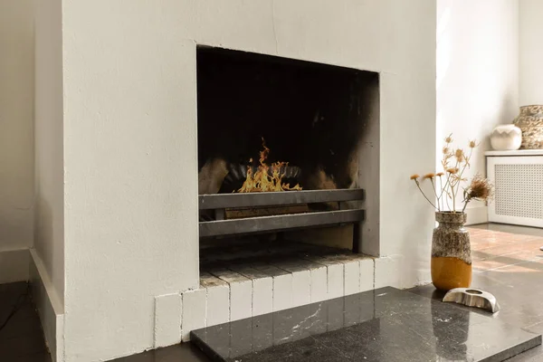 a fireplace in a room with white walls and black tiles on the floor, there is an open fire place