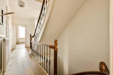 Beyaz duvarları ve ahşap döşemeleri olan bir evin merdiven boşluğunda merdivenler tahtadan yapılmıştır.