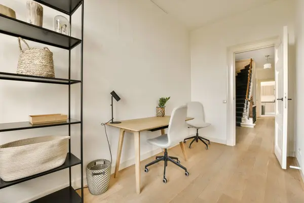 a home office with white walls and wood flooring the room is well lit by natural light from the windows