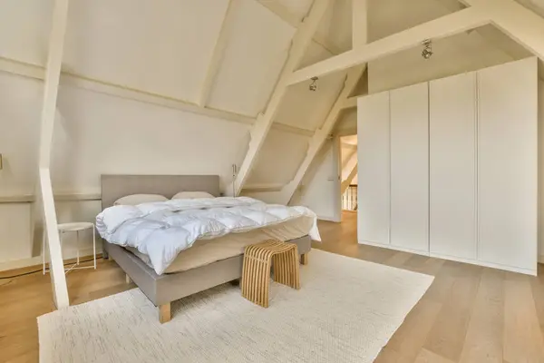a bedroom with white walls and wood flooring in an attic - style home that has been used for many years