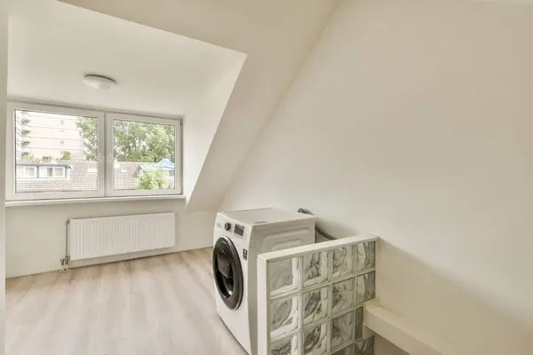 a laundry room with a washer and dryer on the floor in front of an open window looking out