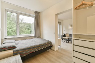 Yatak odası, şifonyer ve penceresi olan bir yatak odası. Görüntü dışarıdan çekiliyor.