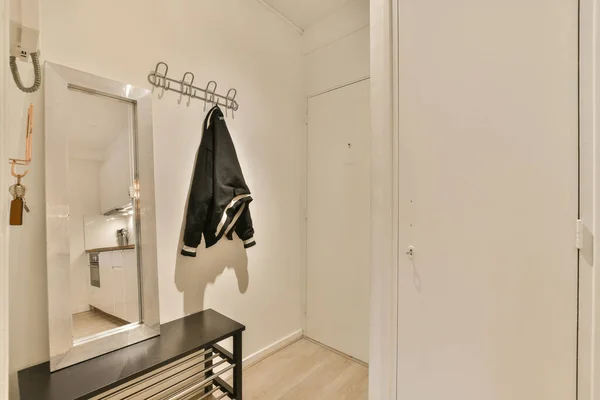 a room with a mirror, coat rack and clothes hanging on the wall next to an open white closet door