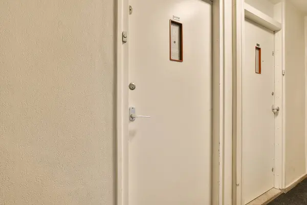 two white doors in a hallway next to a door with a sign on it that says no people are allowed
