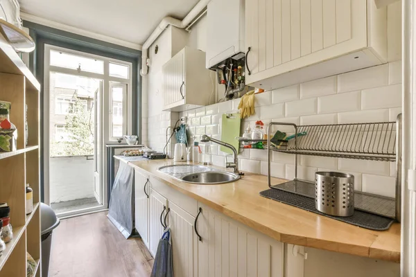 a kitchen with white cupboards and wooden counter tops on the counters in front of the sink is open to the door